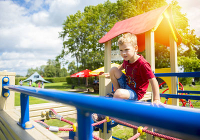 Boy sitting on jungle gym at playground