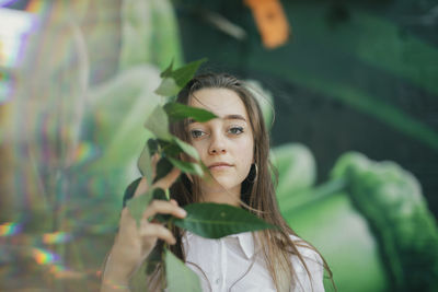 Portrait of young woman holding leaves at outdoors