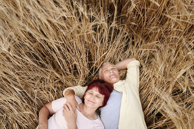 Smiling senior man relaxing with woman on wheat field