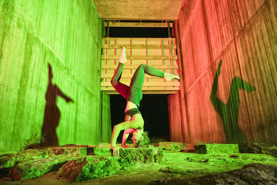 Female acrobat doing headstand on rock