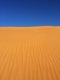 Sand dunes in desert against clear blue sky