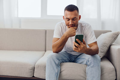 Young man using laptop while sitting on sofa at home