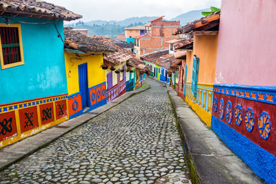 Empty footpath amidst multi colored houses in town
