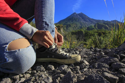 Low section of woman tying shoelace on land