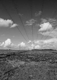 Electricity pylon on field against sky