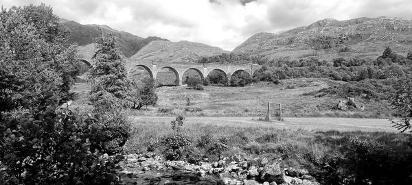 Arch bridge on field against sky