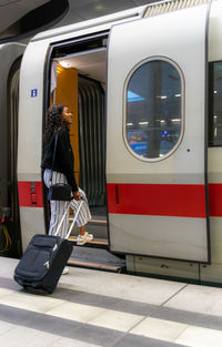 Young woman entering train with luggage