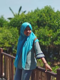 Teenage girl wearing hijab while leaning on railing