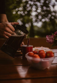 Cropped image of person pouring coffee in cup on table