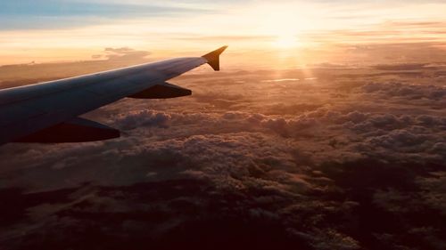 Airplane wing over cloudscape during sunset