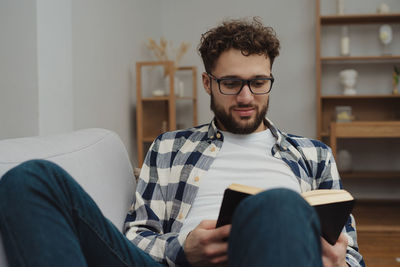 Portrait of young man sitting on sofa at home