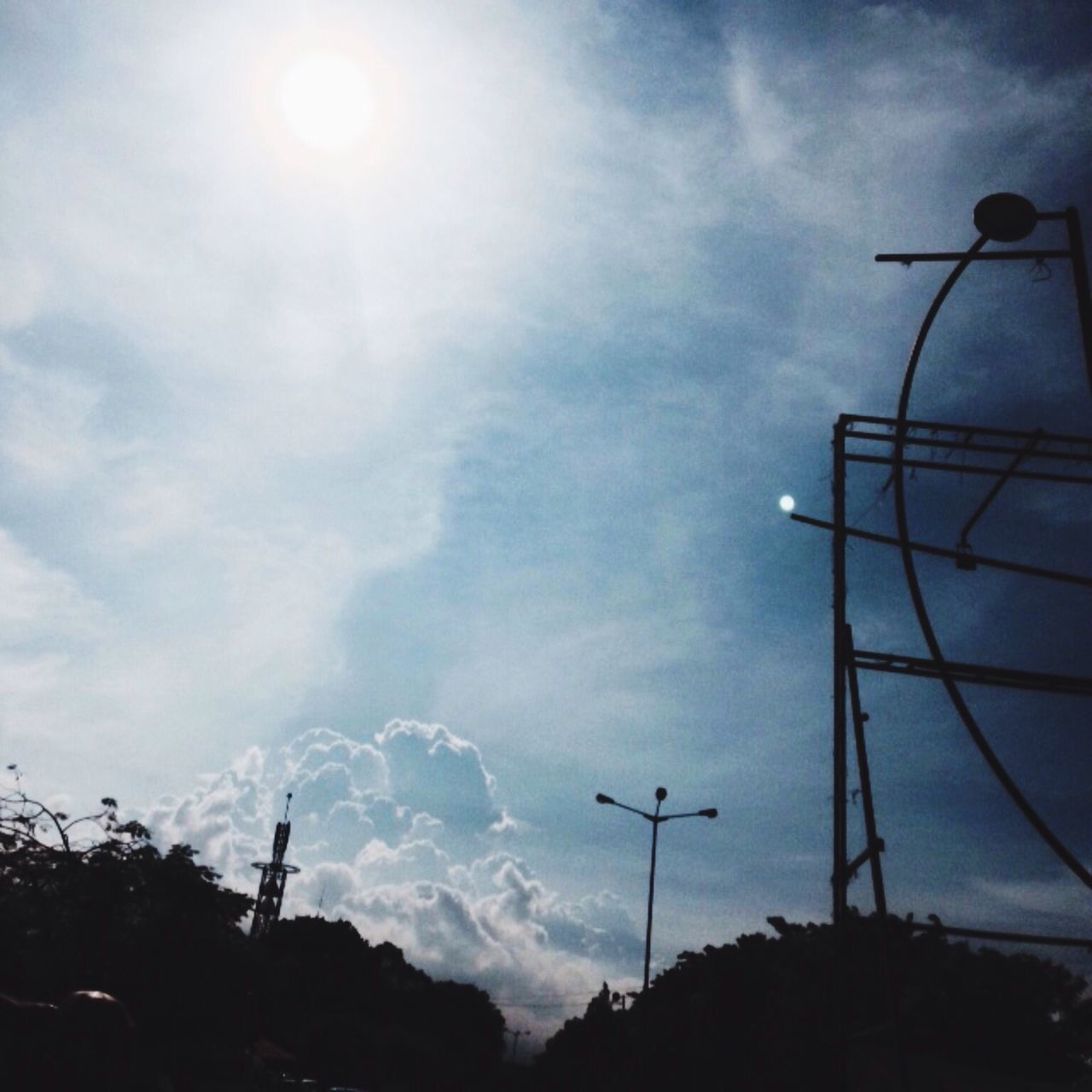 low angle view, sky, street light, cloud - sky, silhouette, lighting equipment, cloudy, cloud, nature, electricity, sun, tranquility, beauty in nature, sunlight, dusk, outdoors, technology, power line, electricity pylon, sunbeam