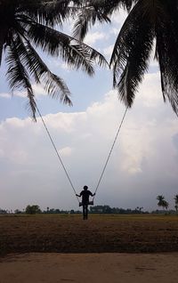Man standing by palm trees on land against sky