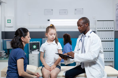 Doctor showing medical report to girl and mother
