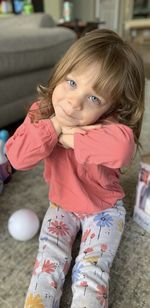 Portrait of cute girl sitting on sofa at home