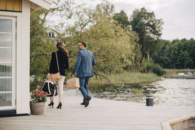 Full length of mature couple walking at holiday villa by lake