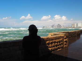 Rear view of man looking at sea against sky