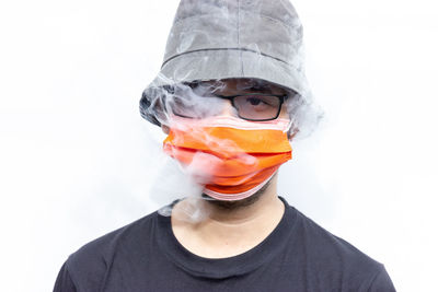 Portrait of man covering face against white background