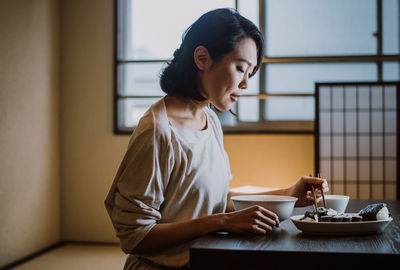 Young woman sitting on table at home