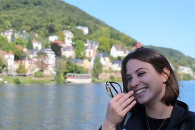 Smiling woman by river against sky