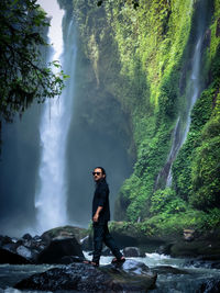 Full length of man standing on rock in forest