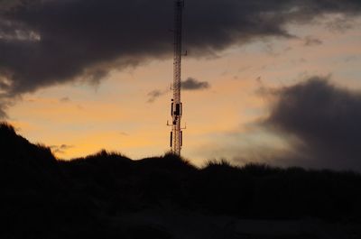 Silhouette of tower against cloudy sky