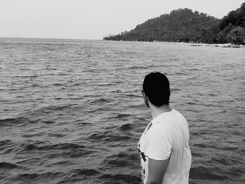 Rear view of man standing in sea against clear sky