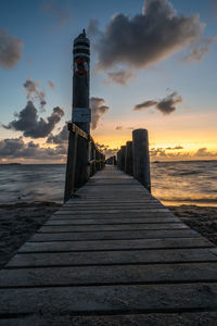 Pier over sea against sky during sunset