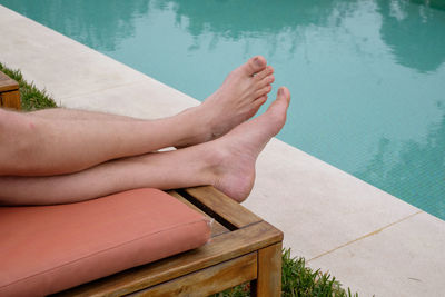 Low section of woman relaxing in swimming pool