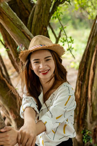 Portrait of young woman wearing hat against trees