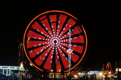 Low angle view of illuminated ferris wheel against sky at night