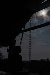 Low angle view of silhouette man hanging against sky at sunset