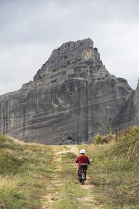 Rear view of man riding motorcycle on mountain against sky