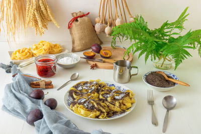 Sweet pasta dessert, noodles with poppy seeds, plum compote from fresh plums, food on the table.