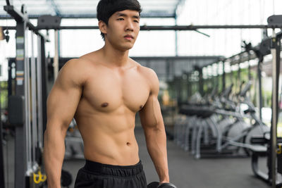 Shirtless young man standing at gym
