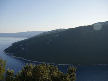 Scenic view of sea and mountains against clear sky