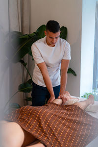 Therapist massaging legs of male client while doing thai massage in spa center