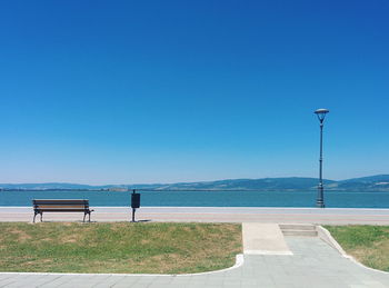 Road by sea against clear blue sky