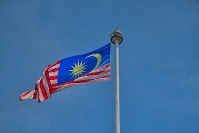 Low angle view of malaysian flag against clear blue sky