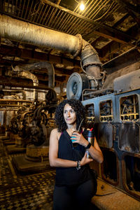 Portrait of a mixed race woman smiling while posing inside an abandoned factory.