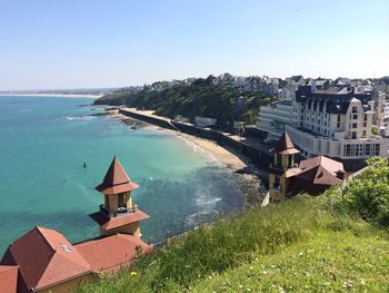 Buildings by sea against clear sky