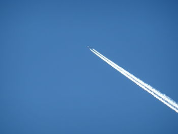 Low angle view of vapor trail against clear blue sky