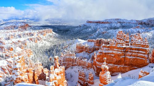 Aerial view of snow covered landscape against cloudy sky