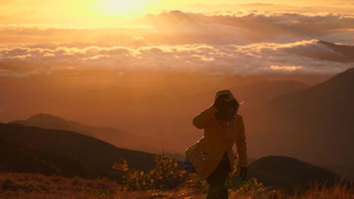 Man standing on field against sky during sunset