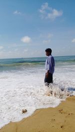 Full length of young man on beach against sky