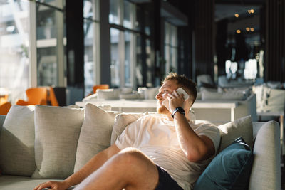 Young woman using mobile phone while sitting on sofa at home