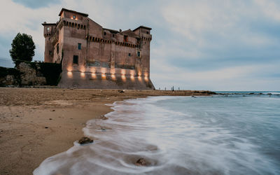 View of building at beach against cloudy sky
