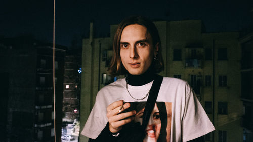 Portrait of young man standing against wall