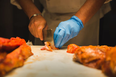 Midsection of man cutting chicken in kitchen