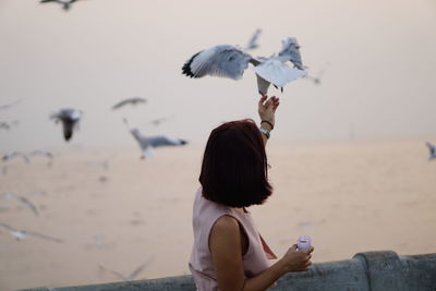 Woman using phone while standing on beach